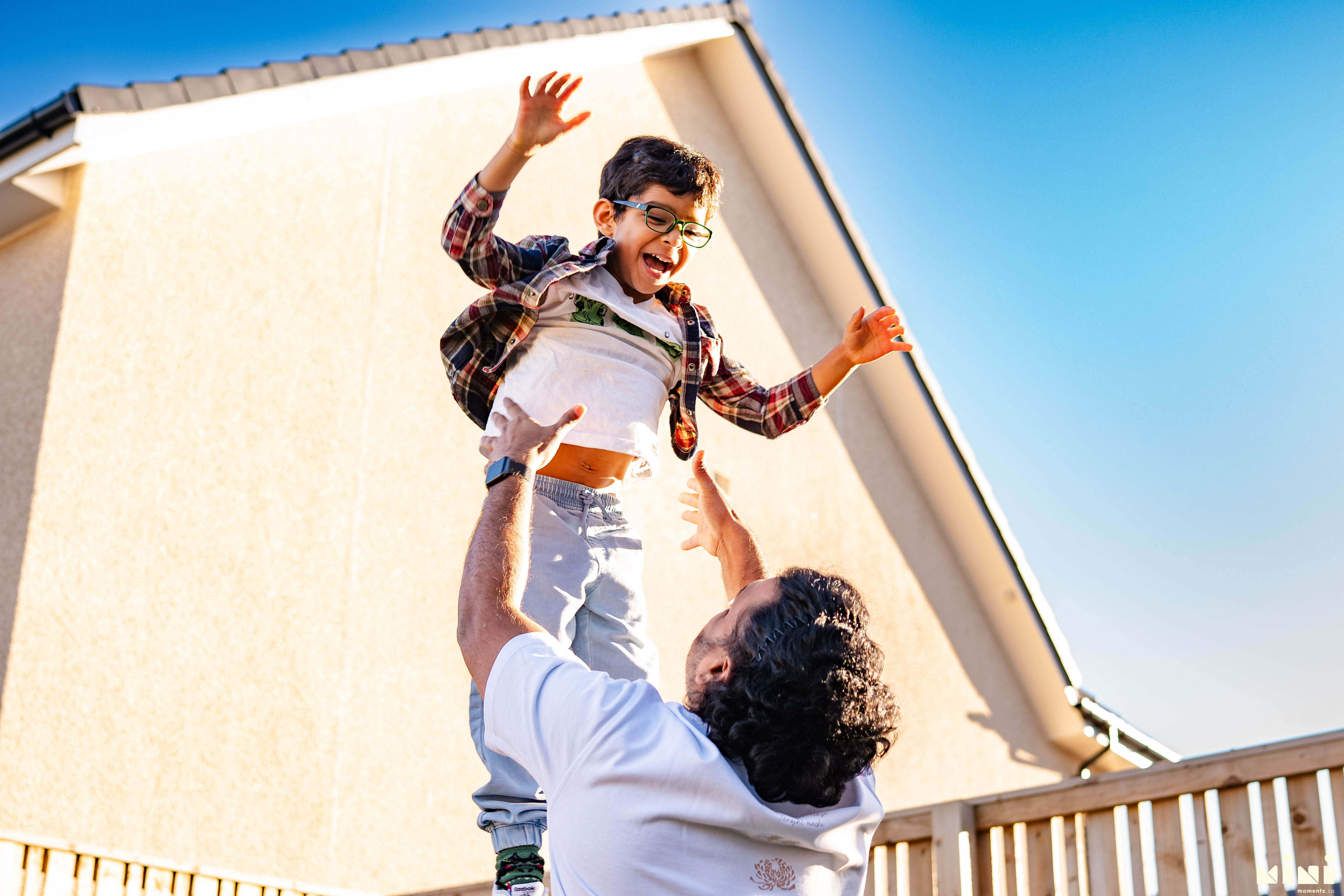 Chaithanya throwing Kiwi into the air outside — a joyful lifestyle moment captured during the MiniMomentz family session in Scotland