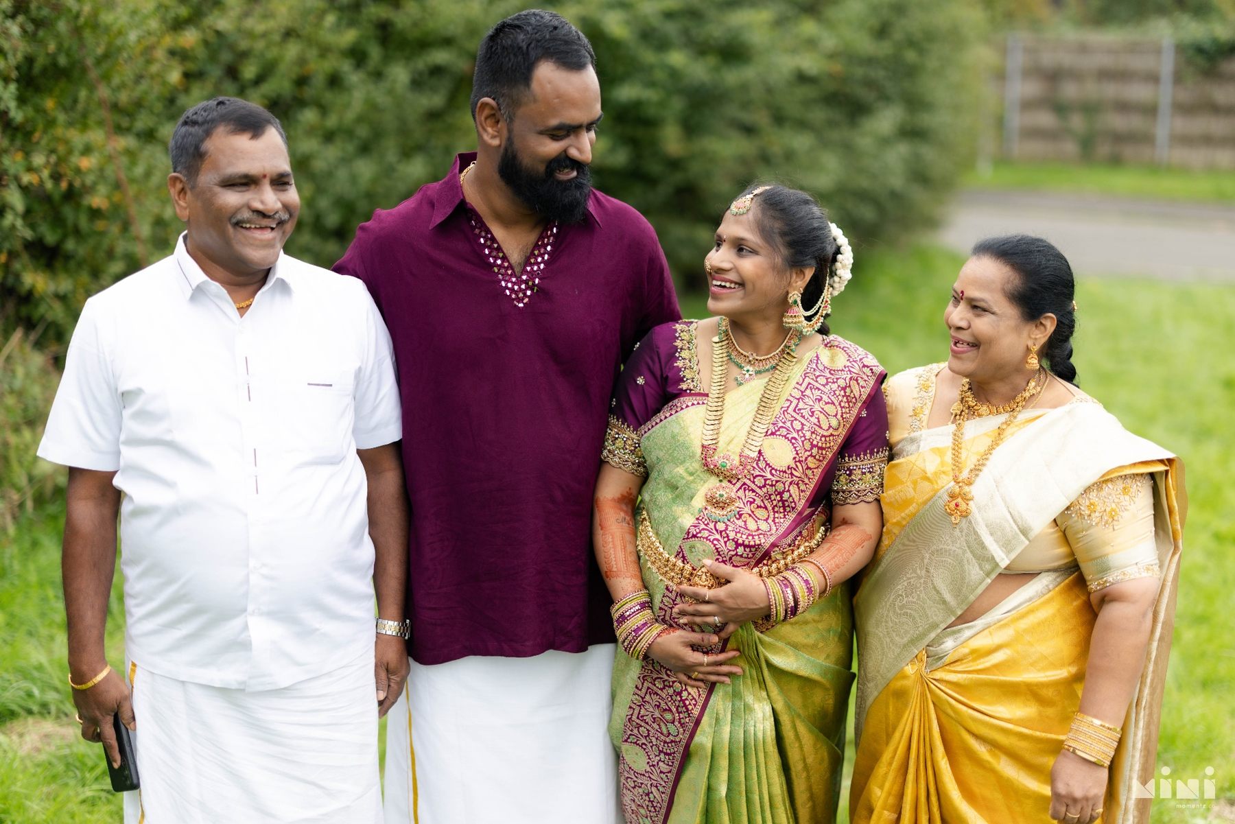 Divya and Ravi laughing with her parents during their outdoor family portraits in Bridgend