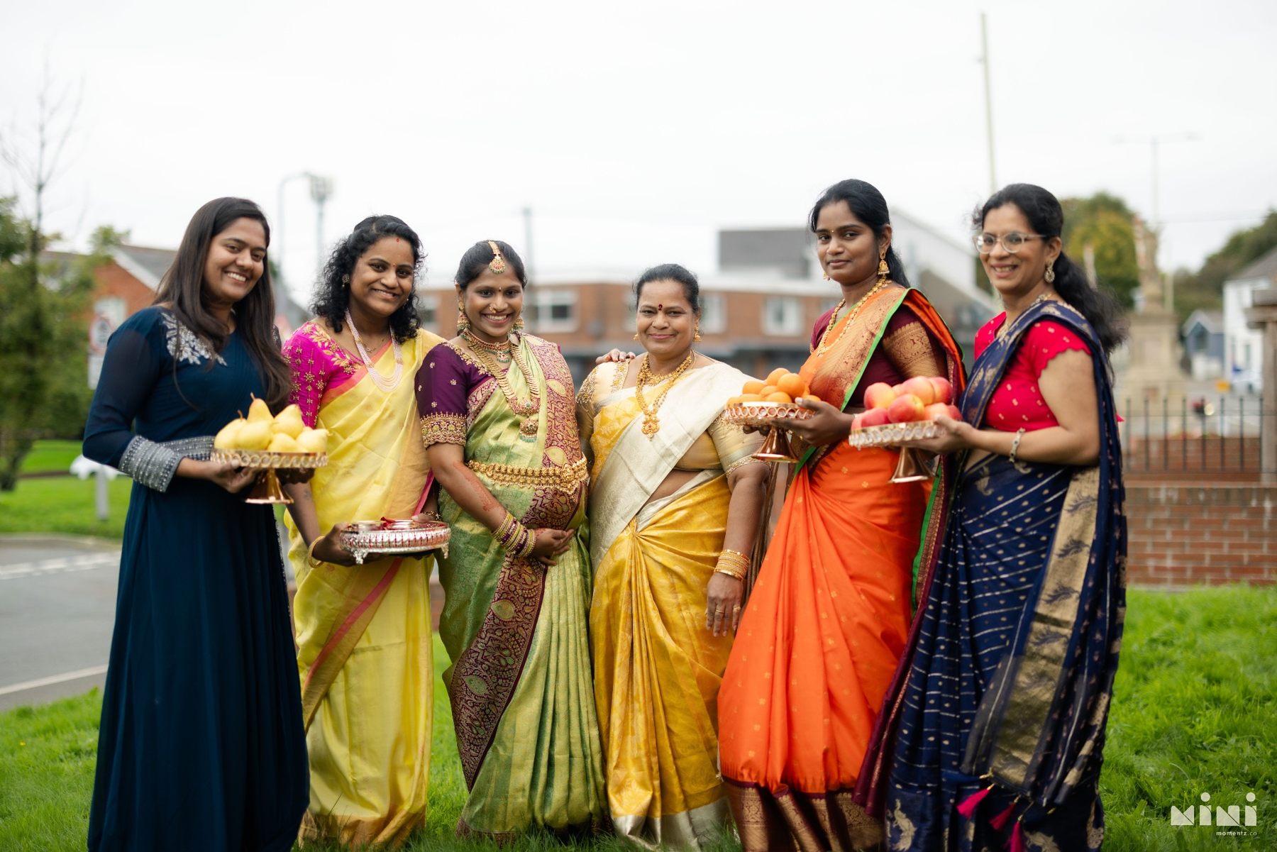 Divya and women from her family smiling together with traditional fruit offerings