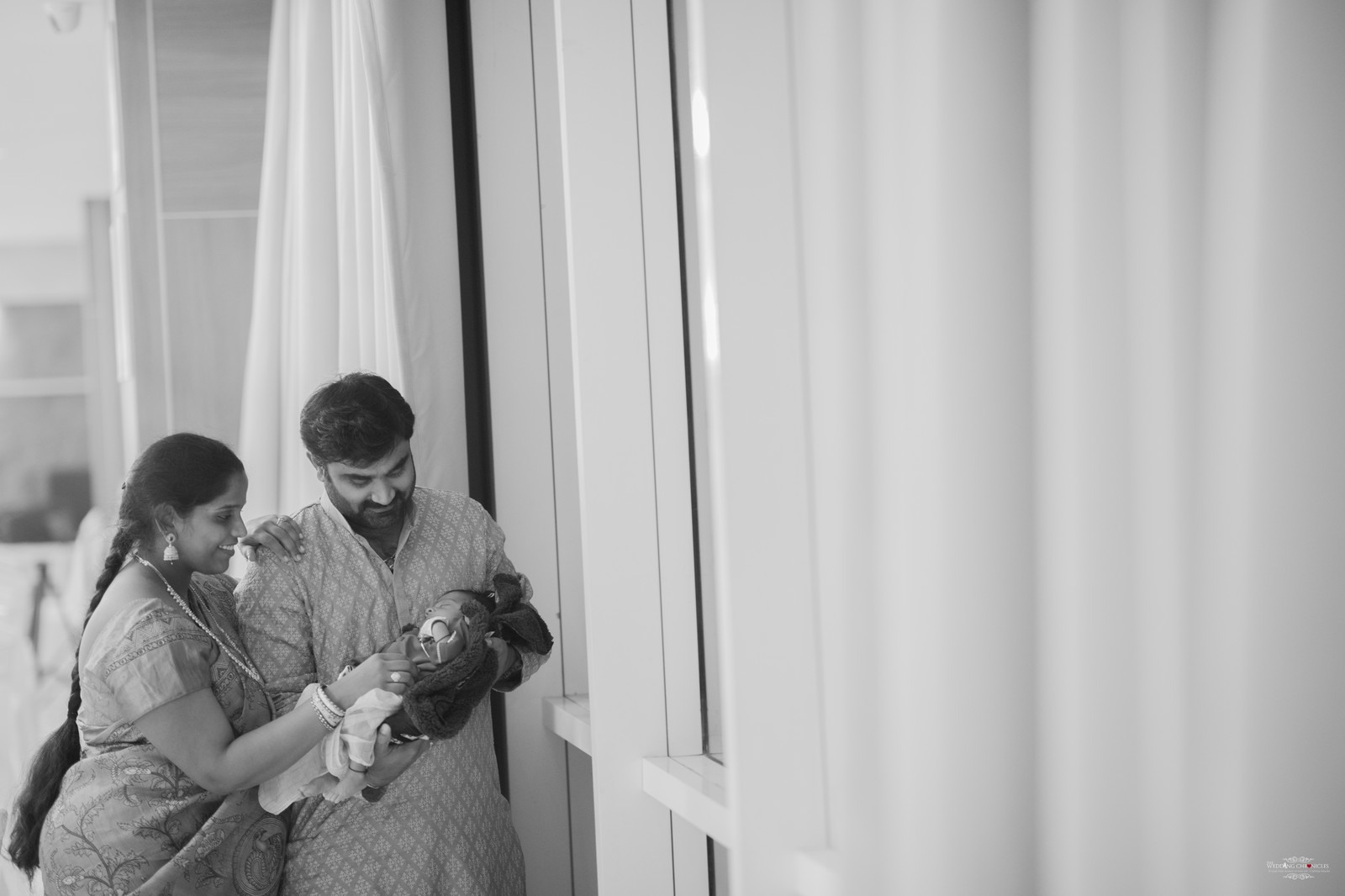 Newborn photography Coventry — parents with newborn by window in black and white, intimate moment MiniMomentz